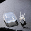 A clear plastic resin ornament shaped like a small elk or deer standing on a dark gray surface.