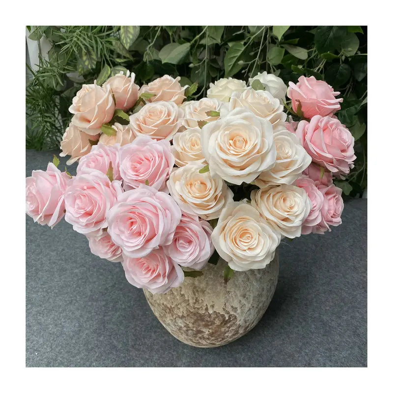 A bouquet of silk roses in shades of peach, cream, and pink arranged in a rustic vase.
