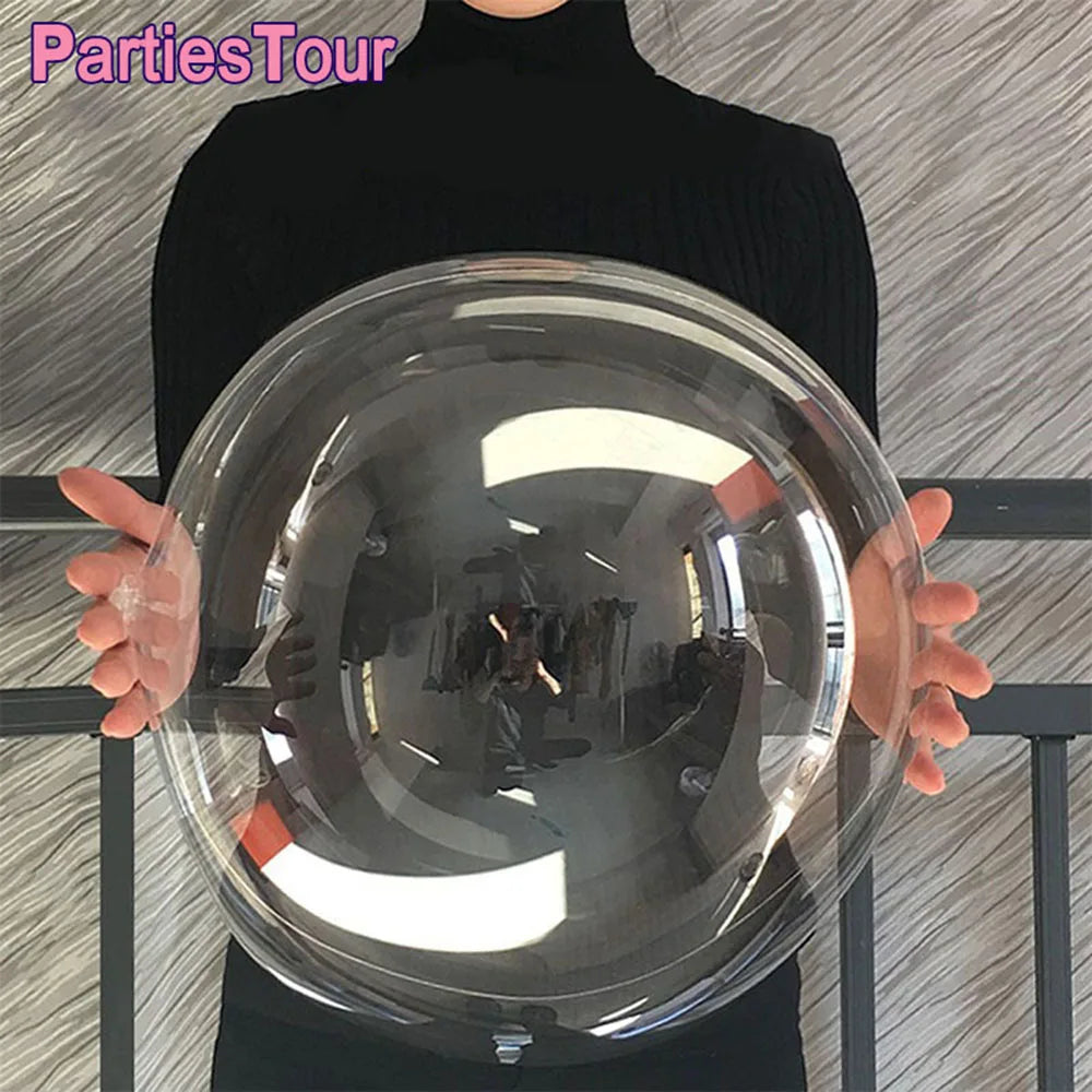 A person holds a large clear balloon for party decor against a light gray background.