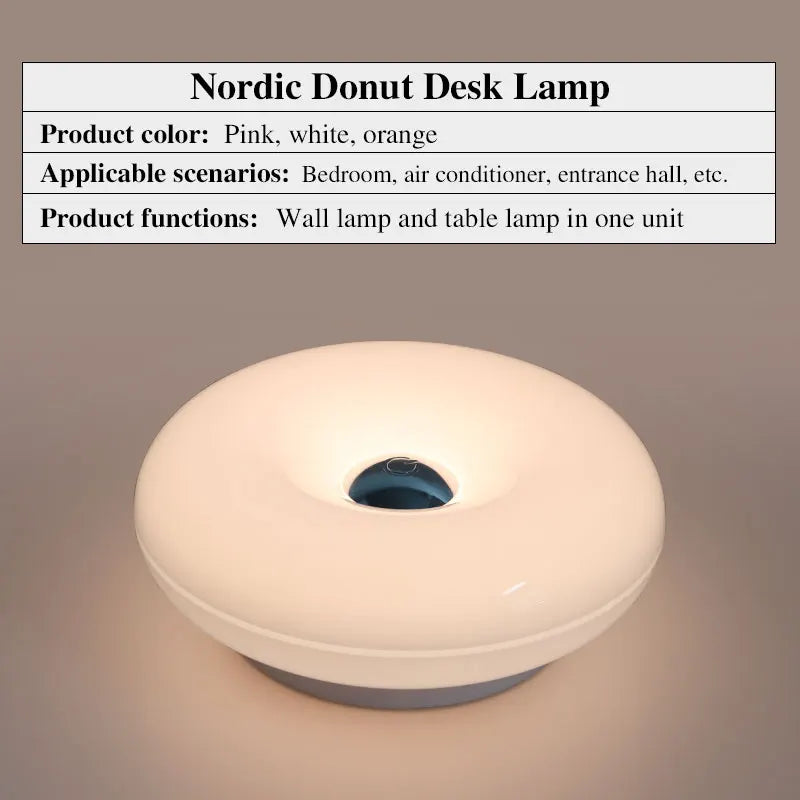 Eine runde, weiße, donutförmige Schreibtischlampe mit blauem Akzentlicht wird auf einer Oberfläche gezeigt.