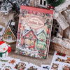 Eine Box mit festlichen Weihnachtsstickern, die eine Weihnachtsdorfszene und saisonale Designs zum Basteln zeigen