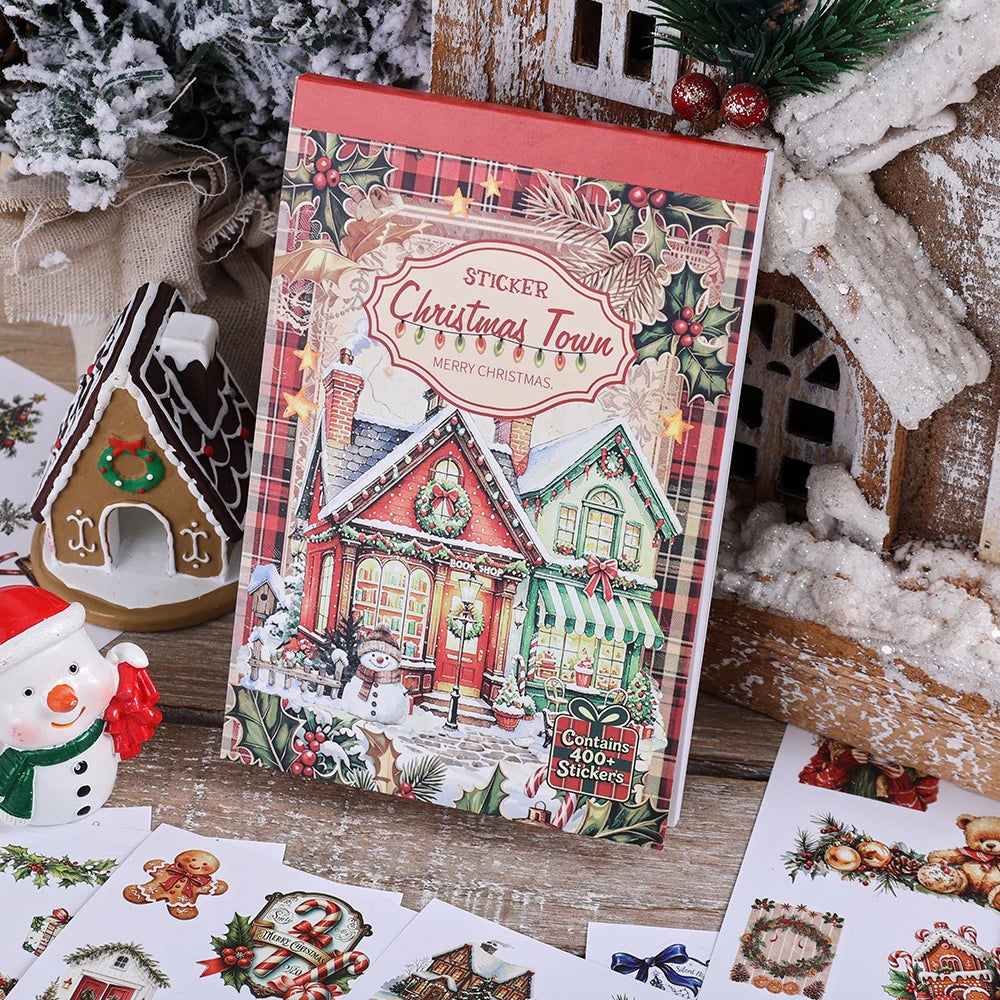 Eine Box mit festlichen Weihnachtsstickern, die eine Weihnachtsdorfszene und saisonale Designs zum Basteln zeigen