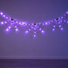 Purple LED string lights shaped like spider webs strung across a dark wall for Halloween decor