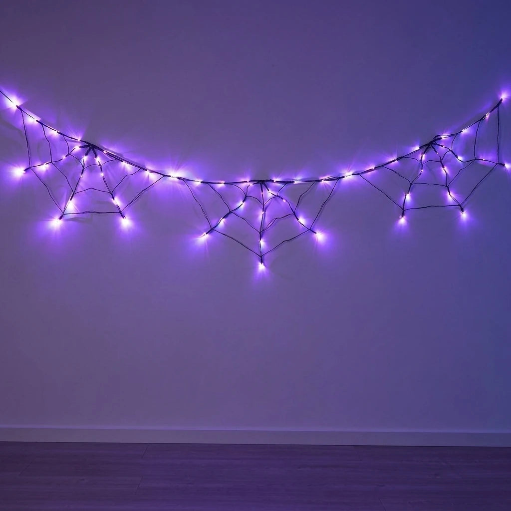 Purple LED string lights shaped like spider webs strung across a dark wall for Halloween decor