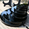 A stack of black obsidian mirrors resting on a wooden surface.