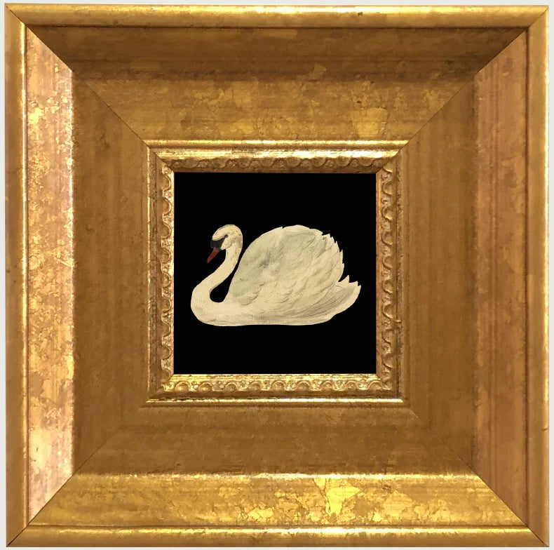 A framed painting featuring a white swan on a black background, set in an elegant gold frame.