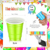 A bright lime green disposable plastic shot cup is shown next to a hand demonstrating its size.