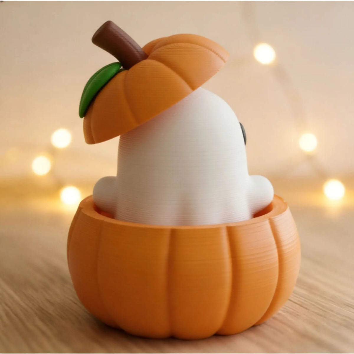 A white elf figure is placed inside an orange pumpkin, decorated with a small green leaf and a brown stem.