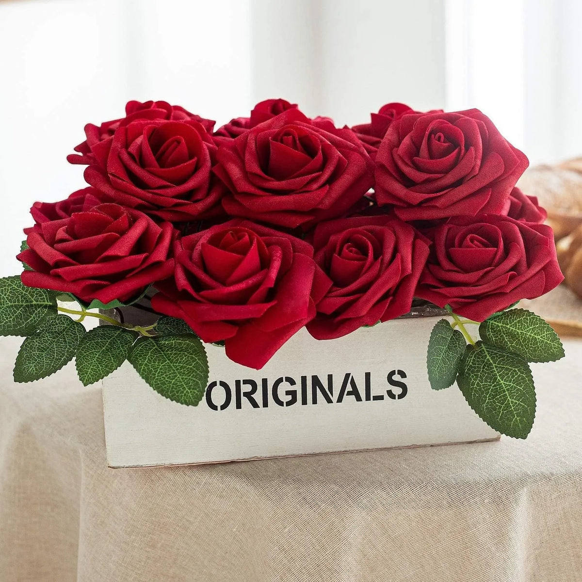 A bouquet of deep red artificial foam roses with green leaves displayed in a wooden box.