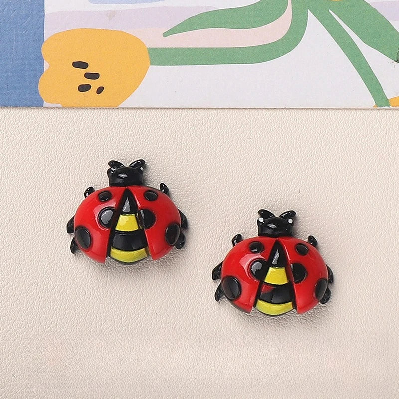 A red and black resin insect magnet shaped like a ladybug or bee, placed on a light background.