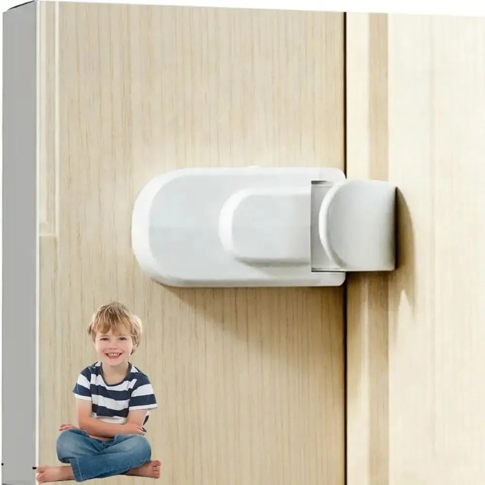 A young boy is standing in front of a light wood cabinet door with a white snap-on child safety lock installed.