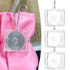 A pink leather bag features a mini transparent CD keychain attached to the strap.