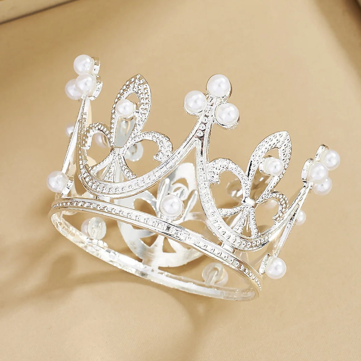 A delicate silver crown made of clear crystals and pearl accents, suitable for cake toppers.