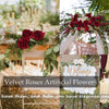 A collection of deep red and pink velvet artificial roses arranged in floral bouquets and decor