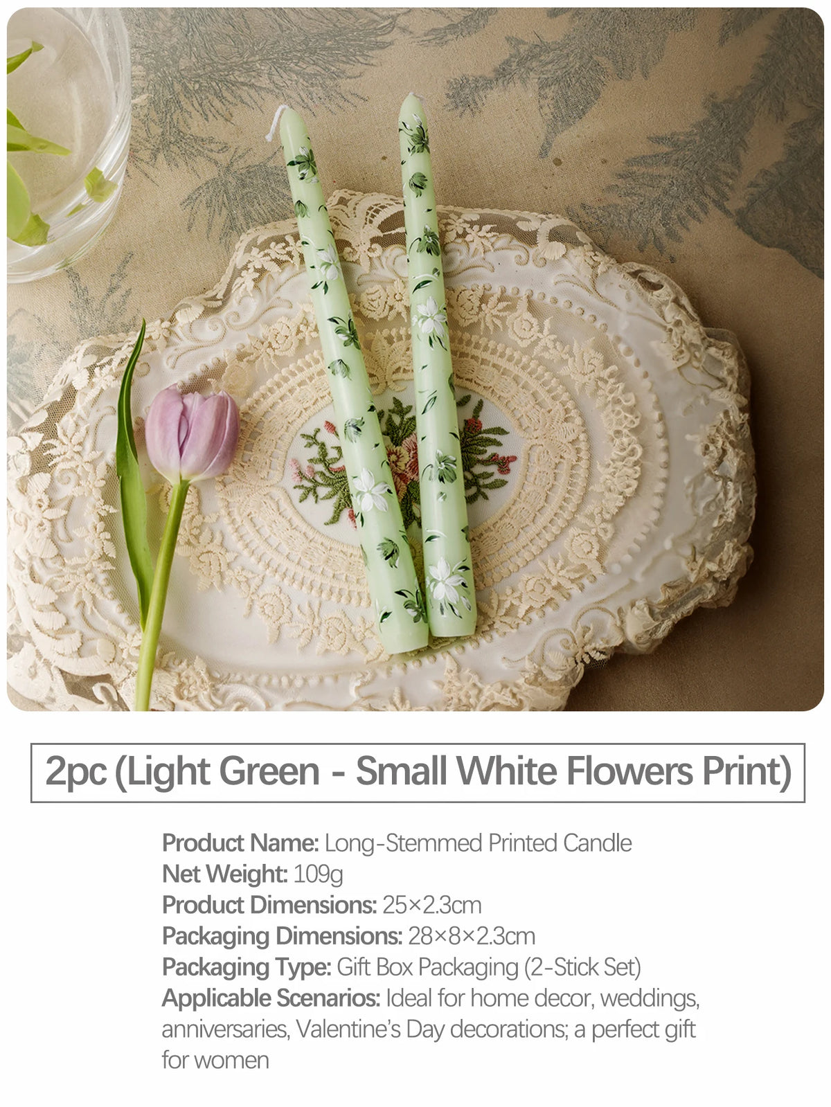 Two long-stemmed printed candles in light green with a small white flowers print displayed on a lace plate.