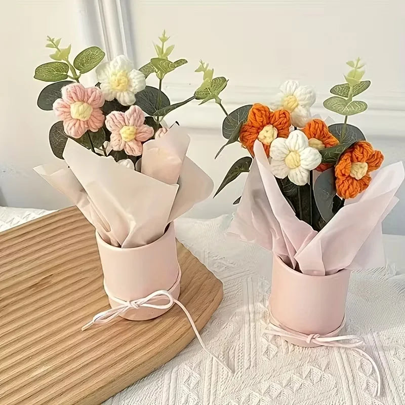 A handmade floral bouquet featuring white and peach flowers with green foliage displayed in pink paper wraps.