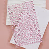 A close-up of pink glitter gems arranged in a diagonal pattern on white paper.