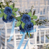A bouquet of artificial blue roses with green leaves tied with light blue ribbon, displayed on a white outdoor chair.