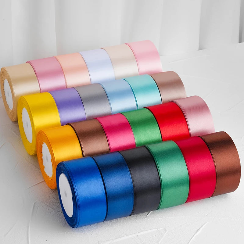 Un ensemble de rubans décoratifs en satin roulés de diverses couleurs, dont rose, violet, jaune, vert et rouge.