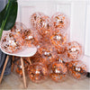 A collection of rose gold sequin balloons in various sizes arranged on a white table.
