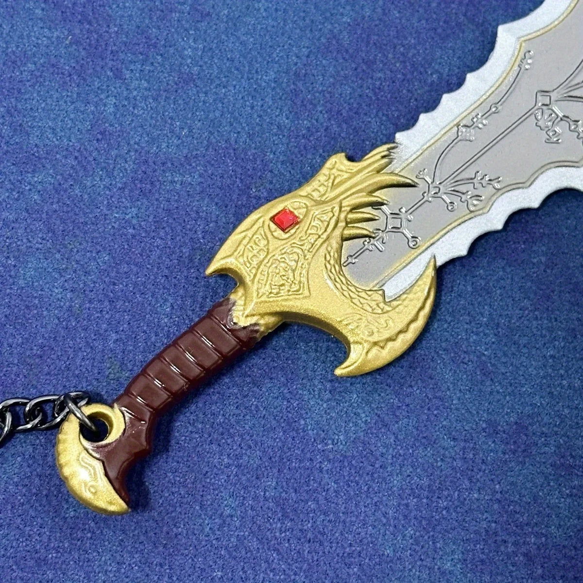 A miniature collectible sword featuring a golden dragon head and silver blade with a dark brown hilt on a blue background.