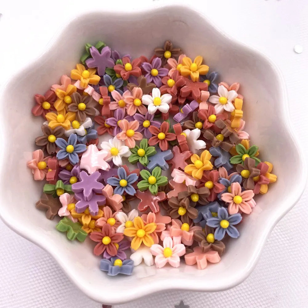 A bowl filled with colorful 3D resin flower gems in shades of yellow, pink, purple, and brown for crafts.