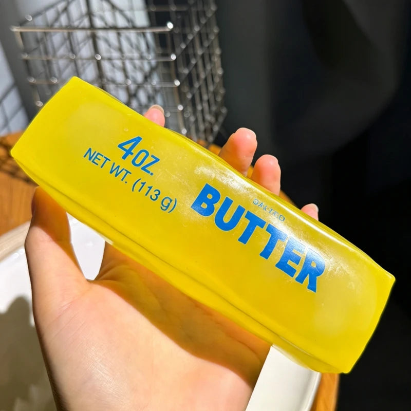 Une main tient un jouet anti-stress jaune étiqueté beurre de 40 oz net