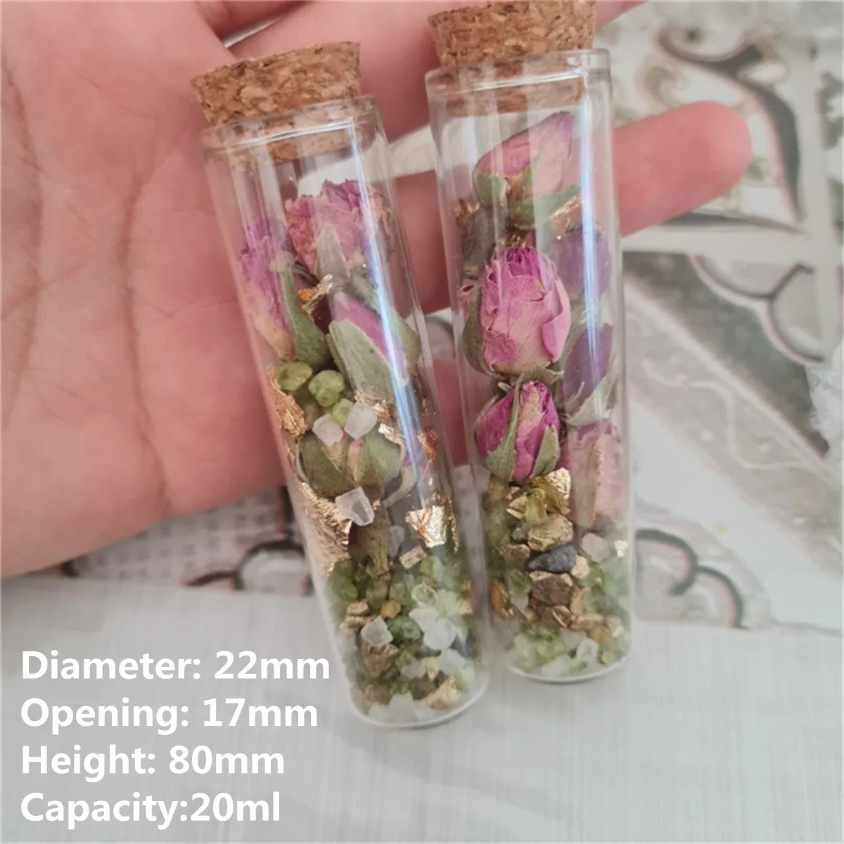 Two small glass bottles with cork stoppers filled with dried flowers and greenery