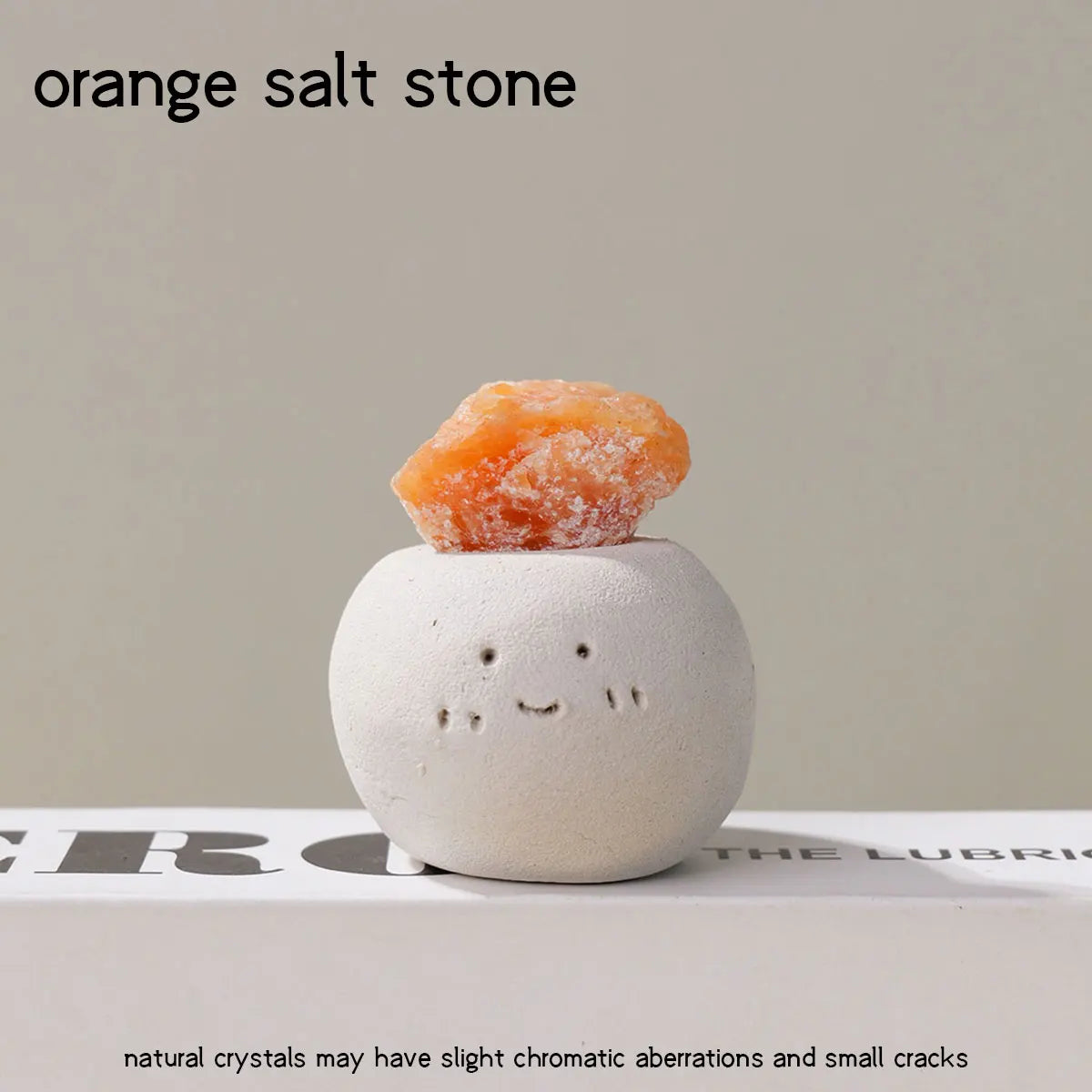 An orange salt stone resting on a white, smooth decorative stone.