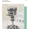 A silver mechanical piston skull sculpture with a gear base, displayed on a white surface.