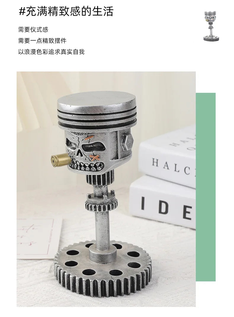 A silver mechanical piston skull sculpture with a gear base, displayed on a white surface.