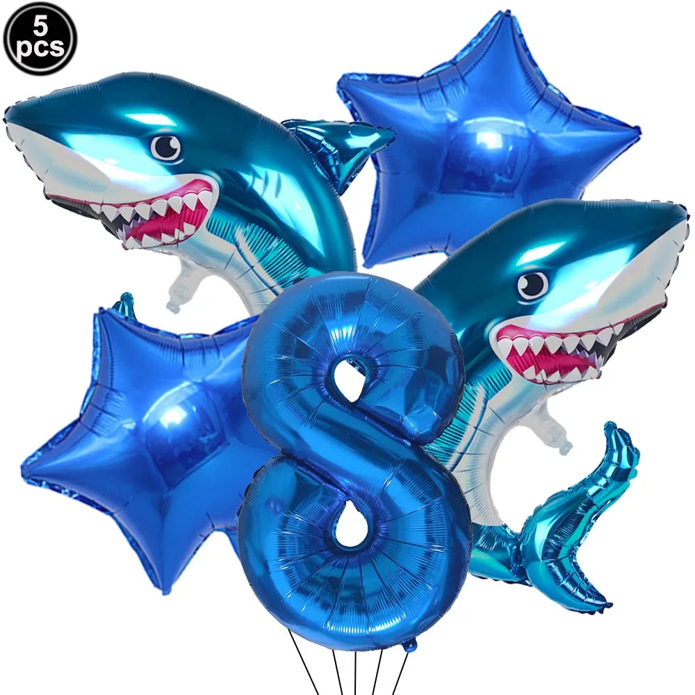 A collection of blue shark foil balloons and a blue number eight balloon for an ocean-themed party decoration.