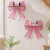 Pink cherry-shaped wooden wall shelves with tassels mounted on a white textured wall.