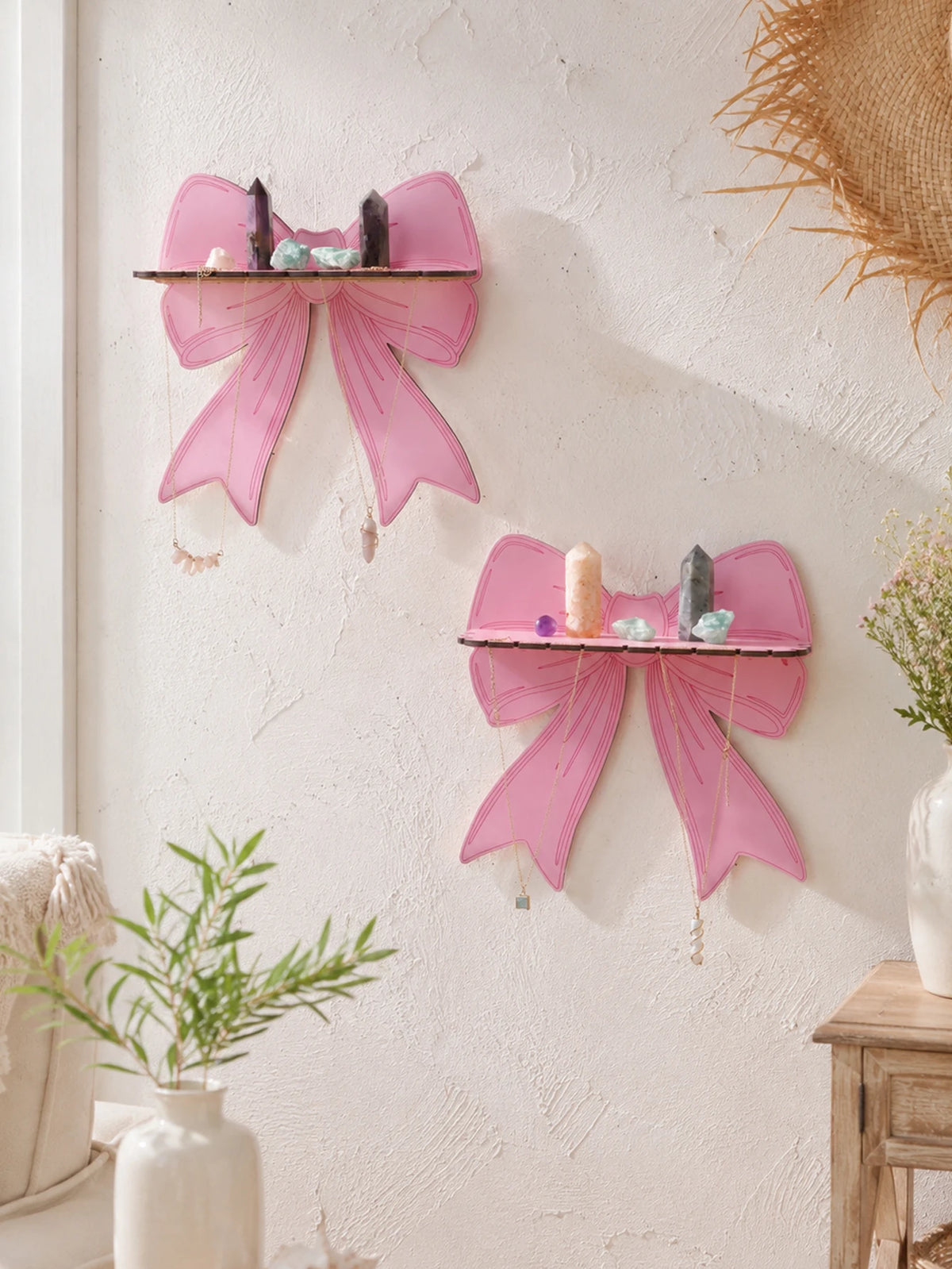Pink cherry-shaped wooden wall shelves with tassels mounted on a white textured wall.
