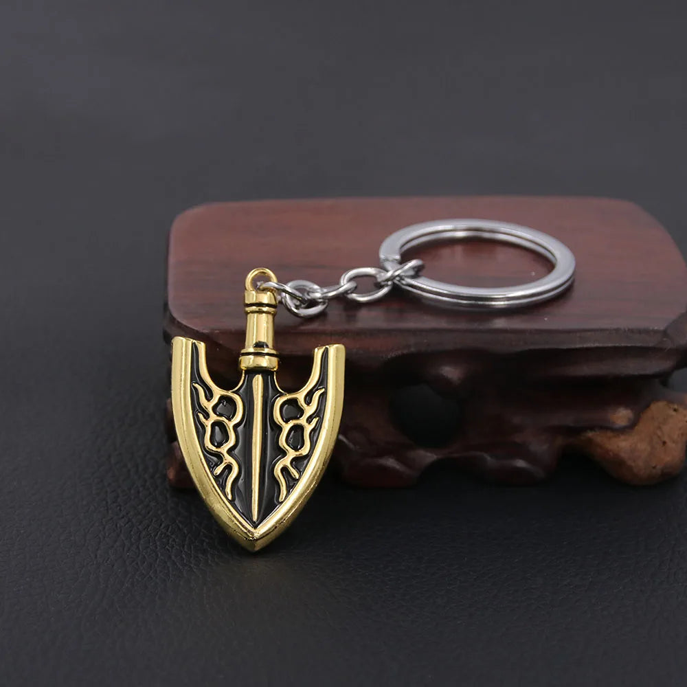 A gold-colored arrow metal keychain with a black design is resting on a dark brown wooden surface.