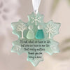 A teal snowflake sea glass ornament with a silhouette of two people inside, hanging by a white string.