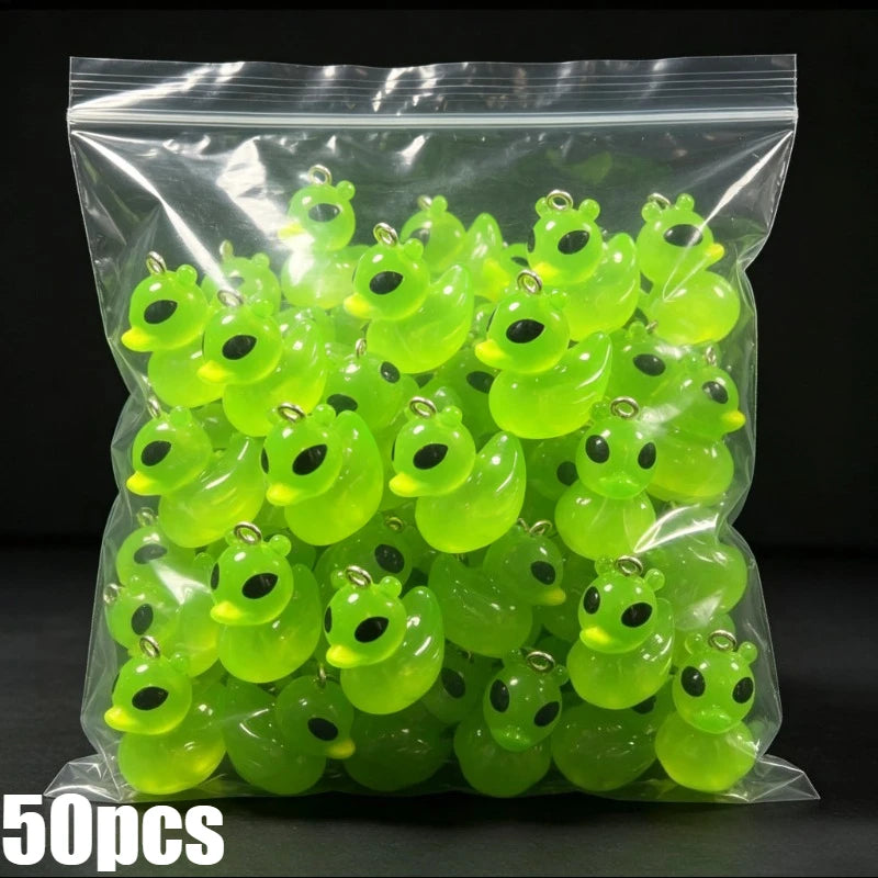 A clear plastic bag filled with fifty glow-in-the-dark resin charms shaped like alien cats and ducks.