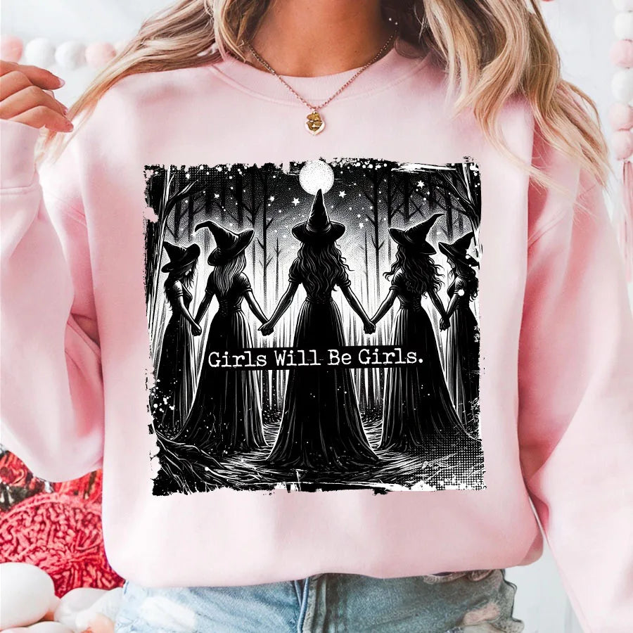 Pink sweatshirt featuring a black and white graphic of four witches standing together with the text Girls Will Be Girls.