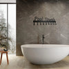 Une baignoire moderne blanche devant un mur texturé gris avec un ensemble de crochets en métal noir.