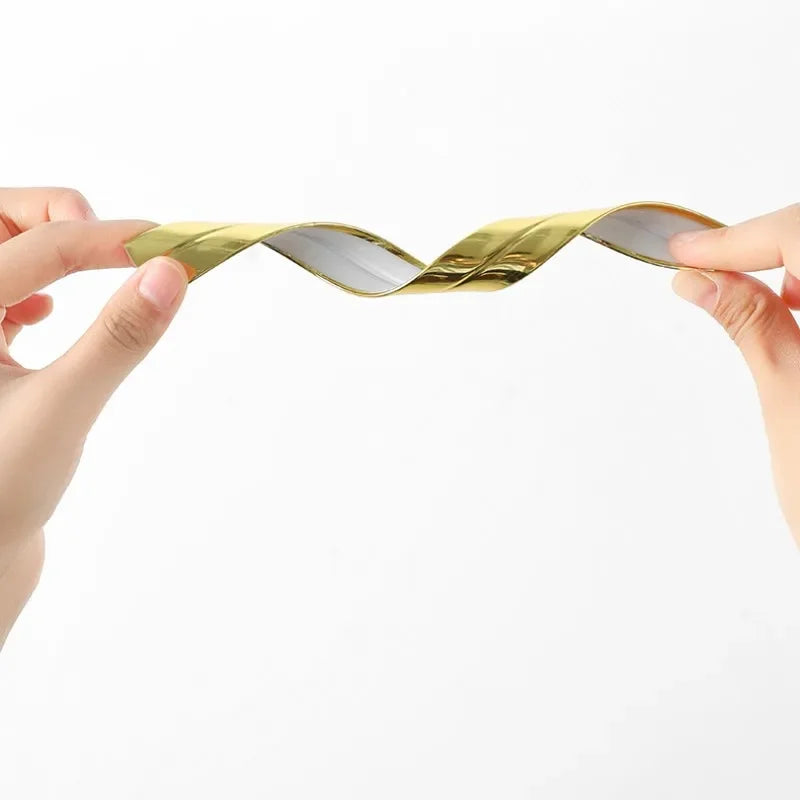 Hands are demonstrating a gold-colored self-adhesive PVC edge guard strip for cabinets or tables.