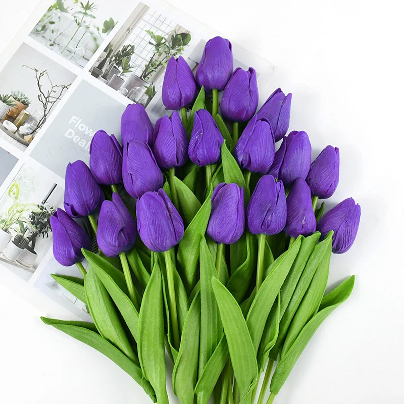 A bouquet of deep purple artificial tulips with green leaves displayed on a white background.