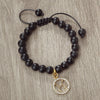 A handmade beaded bracelet featuring natural black stones and a gold zodiac charm.