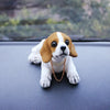A small beagle puppy with white and brown markings is looking directly at the camera on a dark surface.