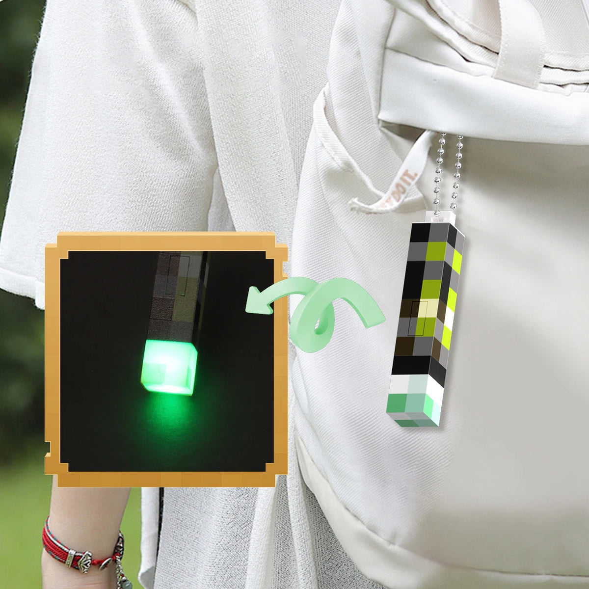 A pixel art flashlight keychain with a green LED light is attached to a white fabric bag.