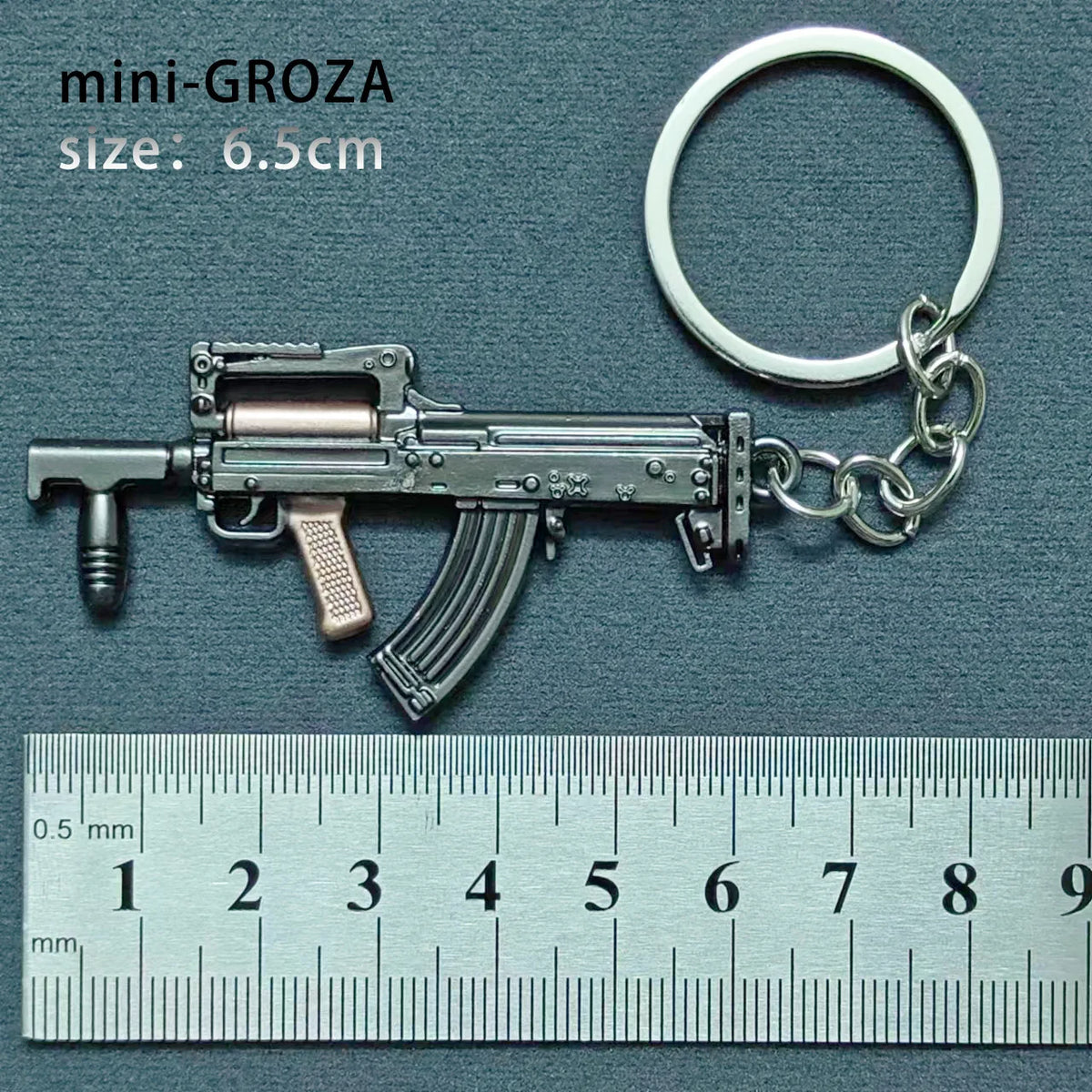 A miniature alloy gun model keychain with a realistic finish, shown next to a ruler.
