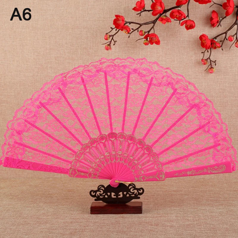 A pink lace folding hand fan with a decorative base and red floral branches in the background.