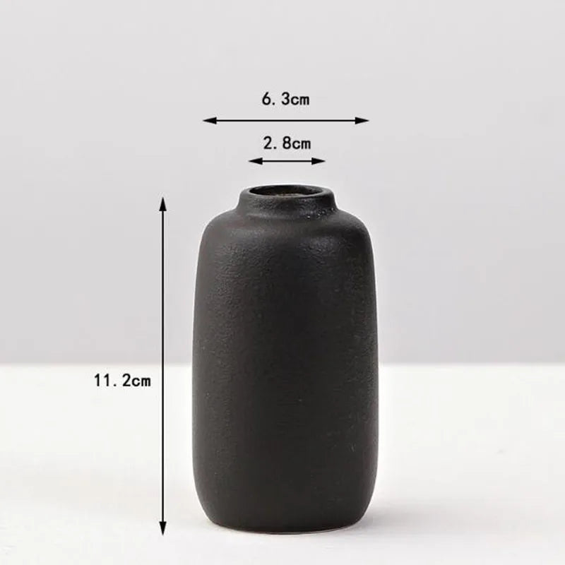 A matte black ceramic vase with a cylindrical shape and a narrow opening, shown against a white background.