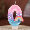 A pink and purple sequined number candle shaped like the number 0, featuring a rainbow accent.