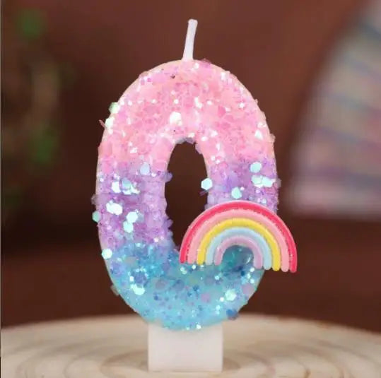 A pink and purple sequined number candle shaped like the number 0, featuring a rainbow accent.