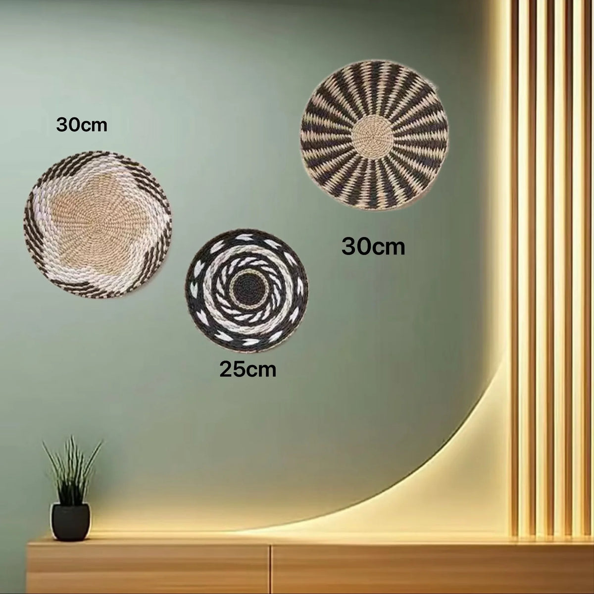 Three round boho straw wall hangings of varying sizes are displayed on a light green wall with vertical lighting.